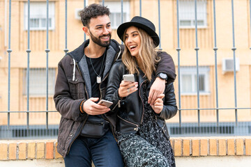 Portrait of laughing young couple with their mobile phones in the city