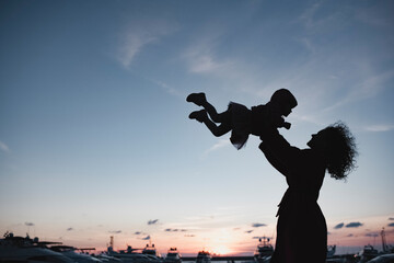 Silhouette of mother playing with her daughter at sunset
