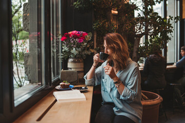 Young woman drinking from coffee cup in a cafe