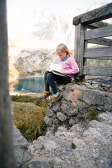 Austria, Tyrol, girl reading book in mountainscape