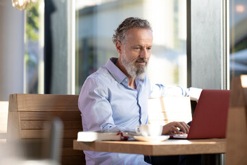 Mature man using laptop in a cafe