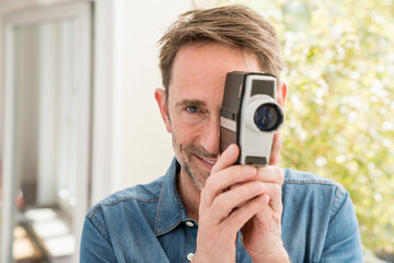 Portrait of smiling man with movie camera looking at viewer