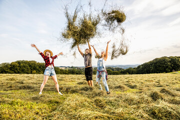 Carefree friends throwing hay in a field