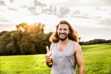 Portait of happy man drinking beer in rural landscape
