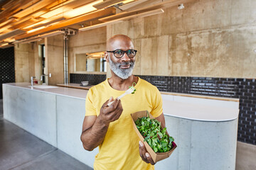 Mature businessman having a salad in modern office