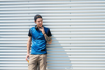 Tattooed young man with headphones and soft drink watching something