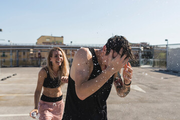 Young man getting splashed by his girlfriend