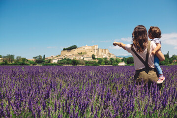 France, Grignan, back view of mother and little daughter standing together in lavender field...
