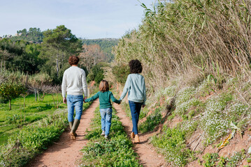 Naklejka na ściany i meble Happy family walking in the countryside, holding hands