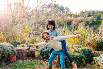 Man carrying girlfriend piggyback in a garden in the countryside