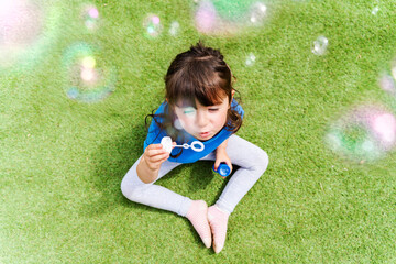 Portrait of little girl blowing soap bubbles