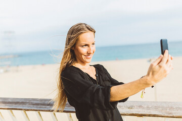 Smiling young woman taking a selfie at the beach