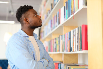 Young man in a library, immersed in studies, surrounded by books, a portrait of dedication.