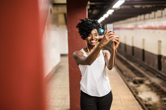 USA, New York City, Manhattan, smiling woman taking selfie at subway station platform