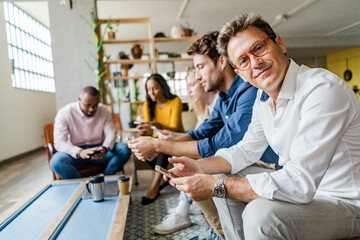 Business team sitting in loft office using cell phones