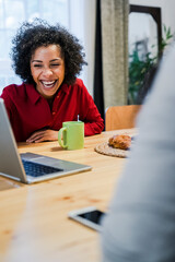 Laughing woman with laptop at table