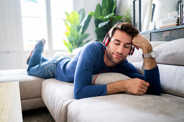 Relaxed man lying on couch listening to music