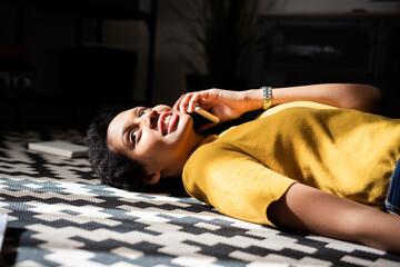 Young woman lying on the floor at home talking on the phone