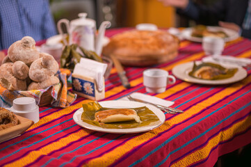 Plate with red tamale on a table with a typical tablecloth.