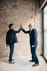 Senior and mid-adult businessman high fiving
