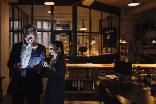 Happy senior buisinessman and girl with hot-air balloon and shining tablet in office