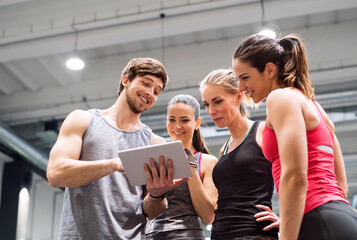 Group of happy athletes with tablet after exercising in gym - obrazy, fototapety, plakaty