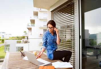 Businesswoman on the phone working on balcony at home