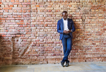 Fototapeta na wymiar Businessman using cell phone at brick wall