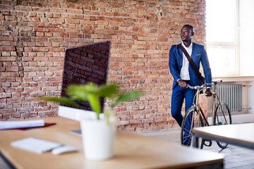 Businessman pushing bicycle in office