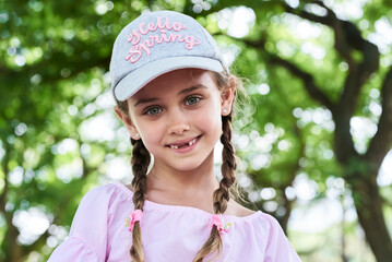 Portrait of little girl with green eyes braids and cap, smiling