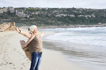 Spain, Menorca, happy senior man standing at seashore in winter