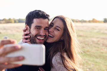 Happy couple taking a selfie in a park
