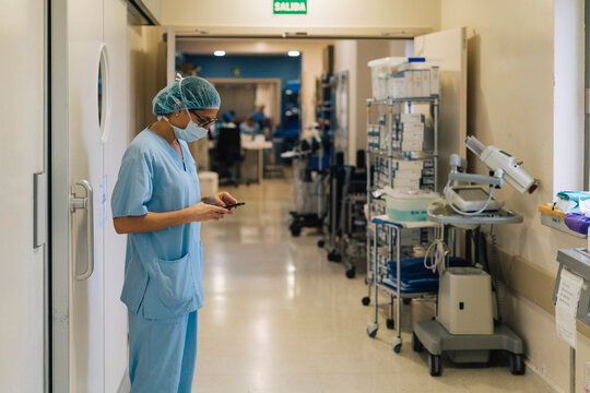 Female doctor using smartphone in hospital, preparing for surgery - Powered by Adobe