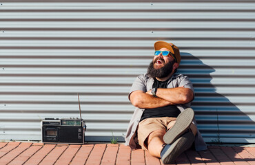 Portrait of bearded man with portable radio enjoying sunlight