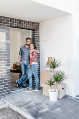 Happy couple standing in door of their new home