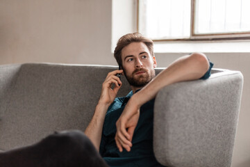 Portrait of young man on the phone sitting on couch