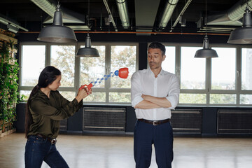 Businesswoman in office hitting businessman with boxing toy