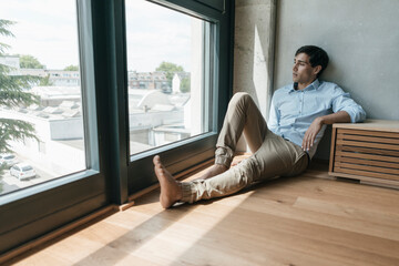 Man sitting on the floor looking out of window