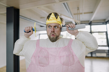 Man dressed up as a ballerina with toy sword in office