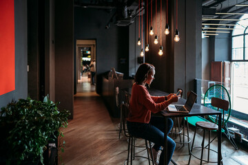 Young woman using laptop and smartphone in a cafe