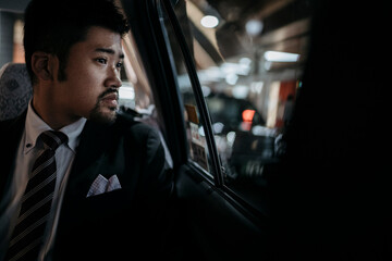 Young businessman in a taxi looking out of window