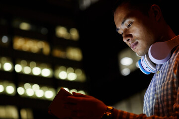 Portrait of young man in the city using tablet at night