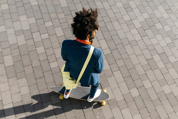 Young businessman riding skateboard on a square