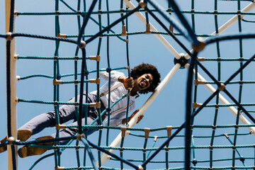 Laughing man standing on edge of jungle gym looking down - Powered by Adobe