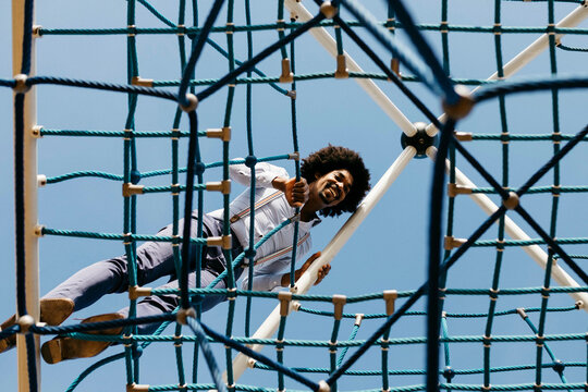 Laughing man standing on edge of jungle gym looking down
