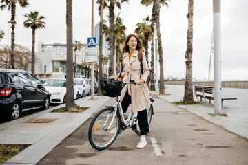 Smiling woman with e-bike on a promenade © tunedin
