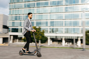 Casual young businessman riding electric scooter in the city
