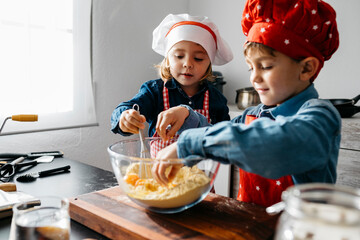 Brother and sister preparing dough in kitchen at home