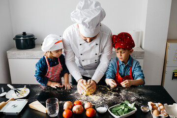 Father with two kids preparing homemade gluten free pasta in kitchen at home