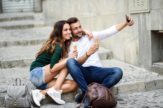 Tourist couple with ice cream cones in the city taking a selfie - Powered by Adobe